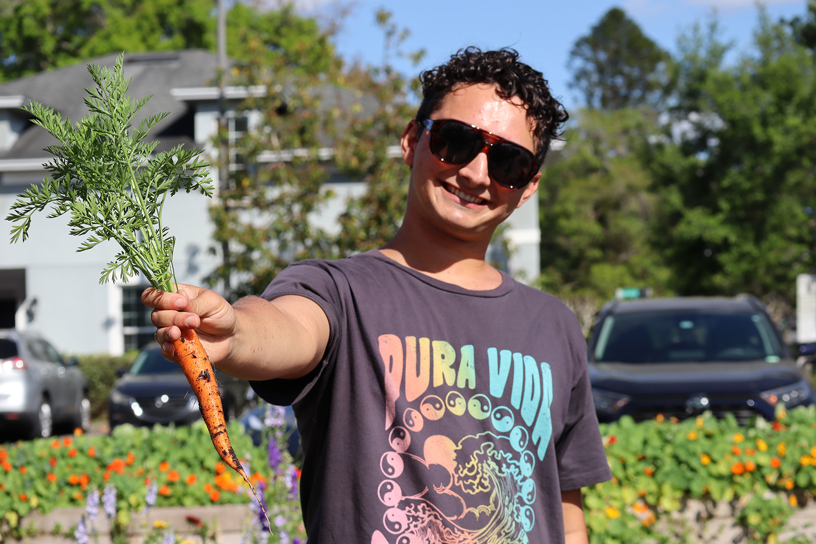 Youth farmer proudly holding a carrot.